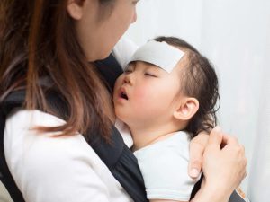 熱を出した子どもを抱っこする母